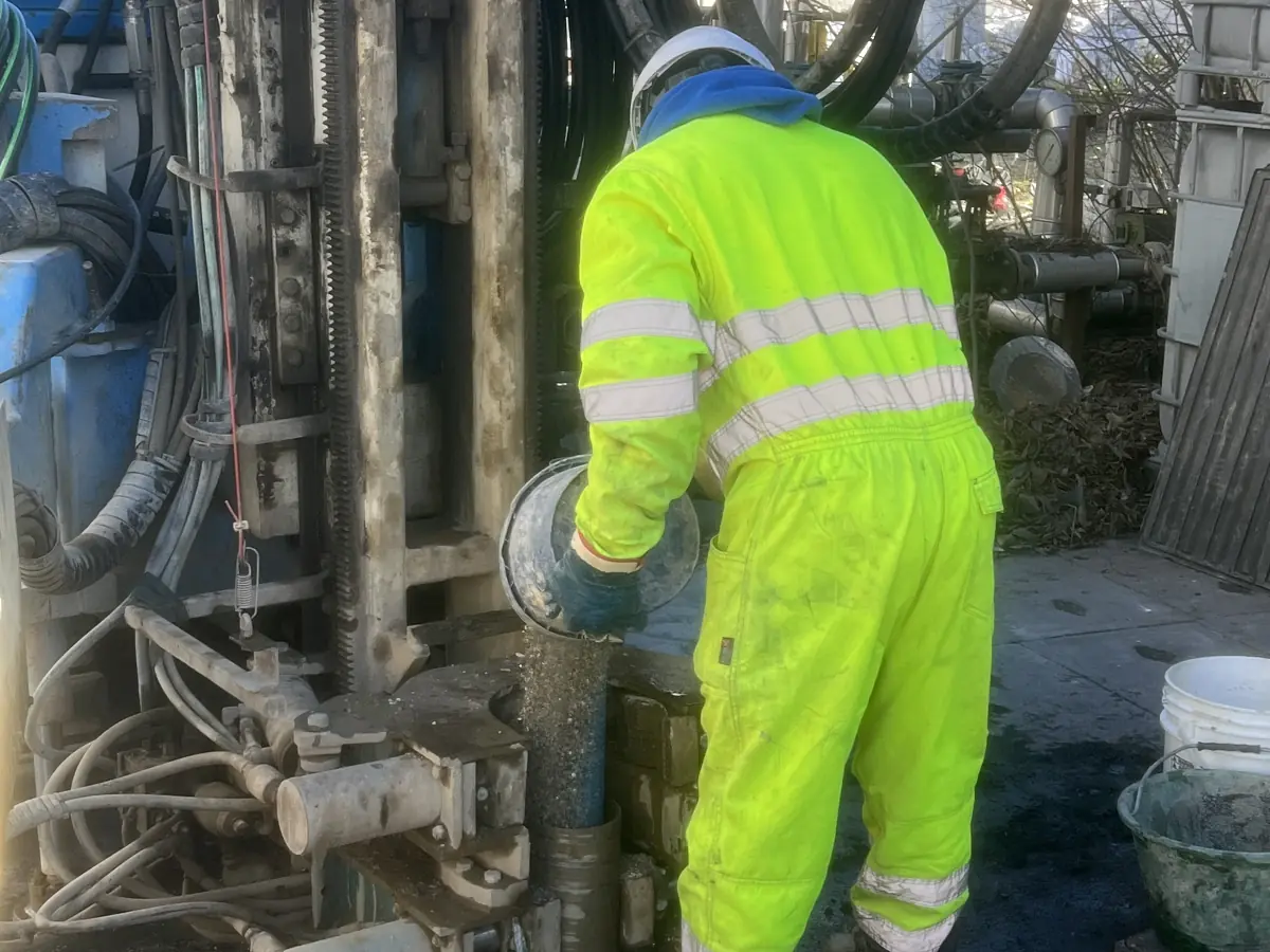 Tecnico in tuta ad alta visibilità al lavoro sulla sonda durante un sondaggio ambientale